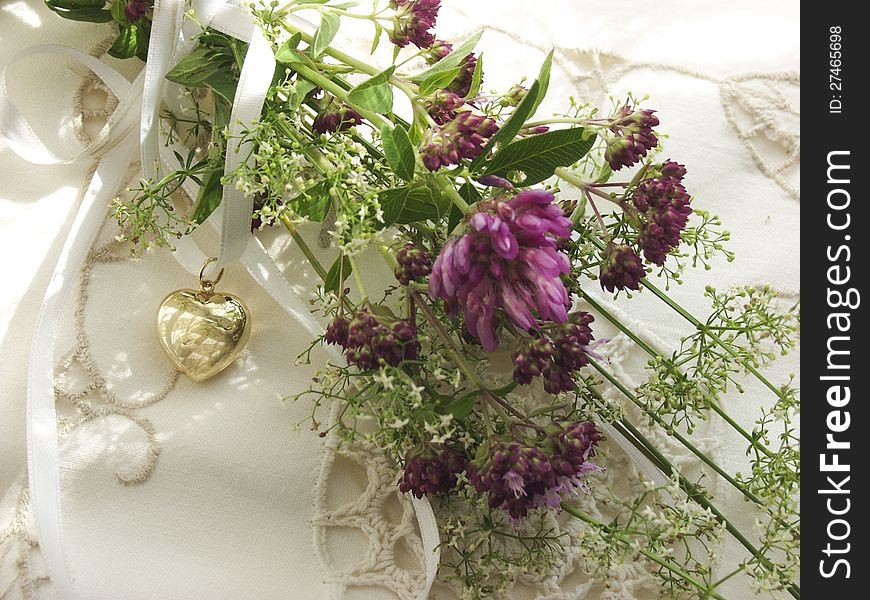 Alpine flowers on a pillow with golden heart in a sunny window. Alpine flowers on a pillow with golden heart in a sunny window.