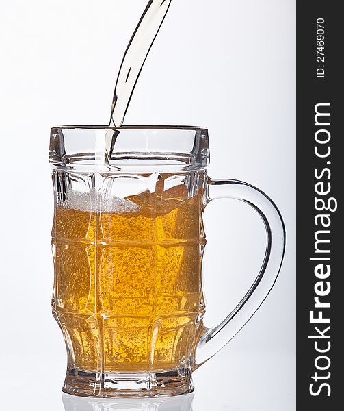 Beer pouring into beer mug on white