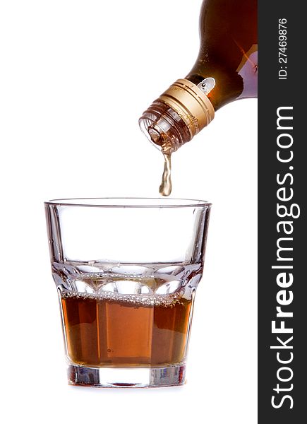 Whiskey being poured into a glass on white background