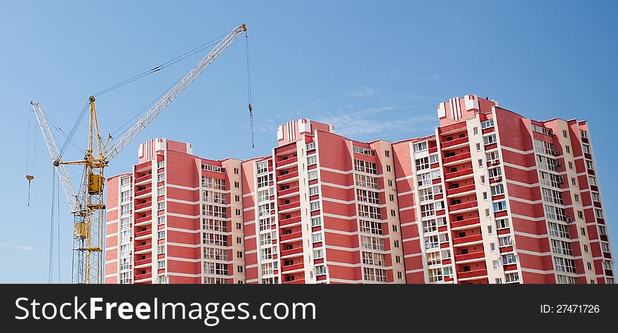 The elevating crane against the dark blue sky, building a monolithic building.