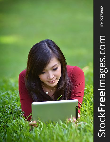 Pretty woman using tablet outdoor laying on grass