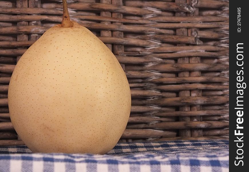 Asian Pear on a blue checked table cloth stood by a willow weave picnic basket. Asian Pear on a blue checked table cloth stood by a willow weave picnic basket