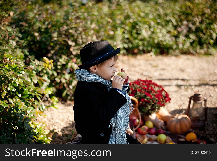 Boy in a black coat and hat at the picnic. Boy in a black coat and hat at the picnic