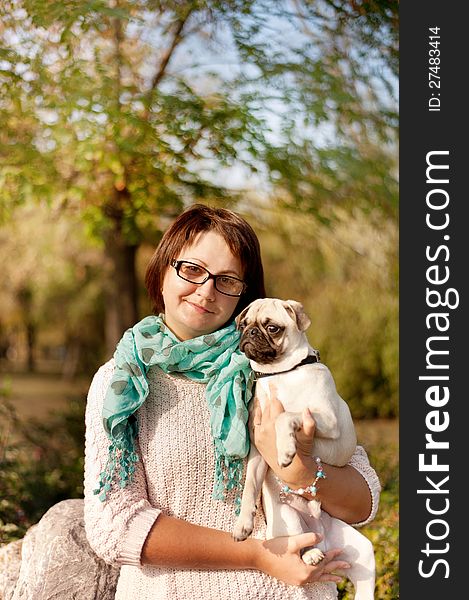 Outdoors woman in glasses holding a pug. Outdoors woman in glasses holding a pug