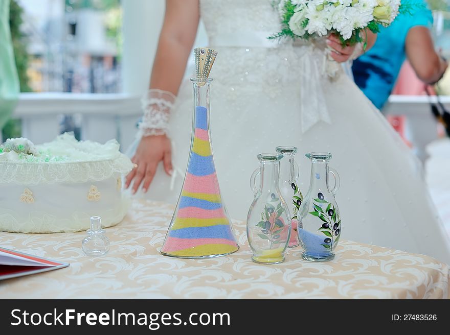 Beautiful bride's hands poured colored sand into a bottle. Beautiful bride's hands poured colored sand into a bottle