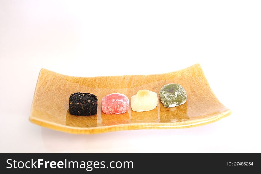 Various colors of Japanese mochi on Japanese square clay plate, on white background.