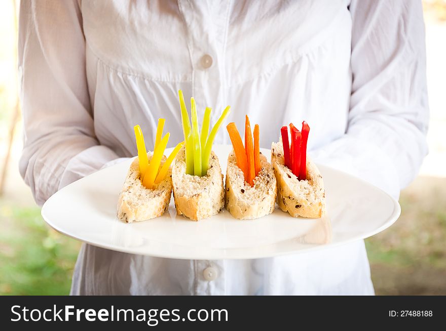 A waitress holding a plate of vegetarian catering food. A waitress holding a plate of vegetarian catering food