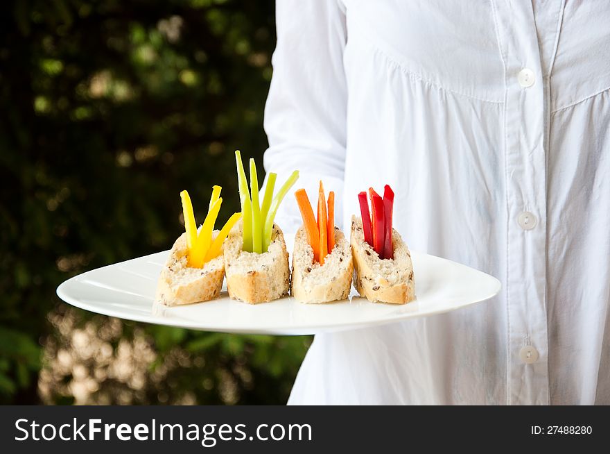 A waitress holding a plate of vegetarian catering food. A waitress holding a plate of vegetarian catering food