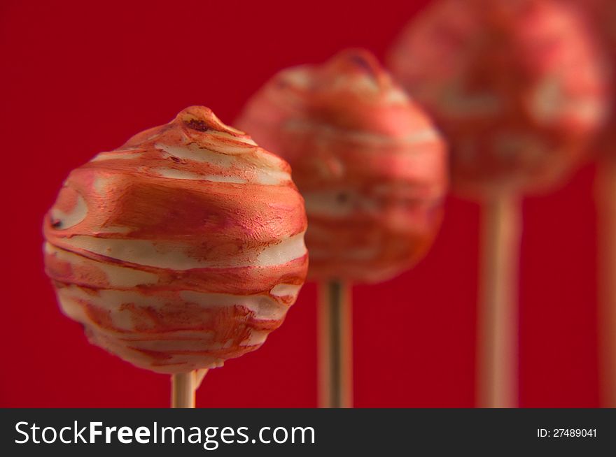 Red cake pops on wooden sticks on red background. Red cake pops on wooden sticks on red background