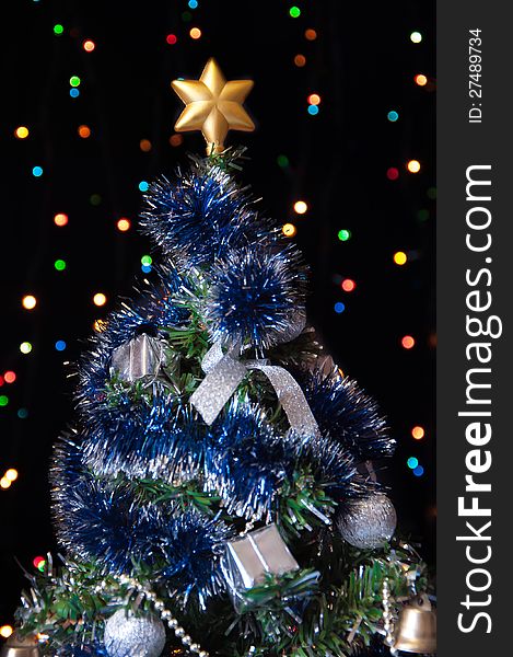 Dressed up fur-tree with the star on the top of his head on a black background with colored lights. Dressed up fur-tree with the star on the top of his head on a black background with colored lights