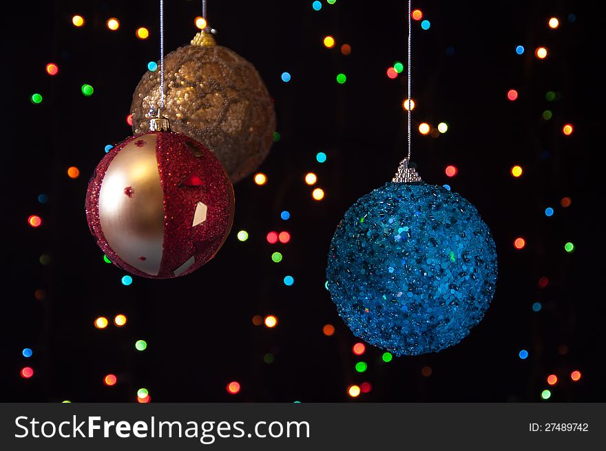 Three Christmas ball on a black background with lights