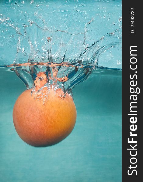 Water splash grapefruit on blue background