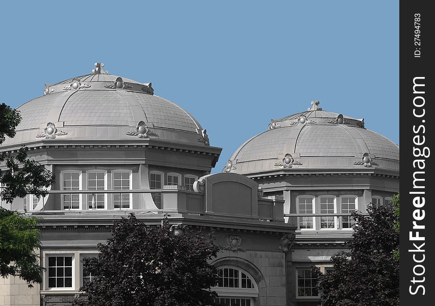 Two building domes of gray concrete and stone, with decorative features.  Against a clear blue sky background. Two building domes of gray concrete and stone, with decorative features.  Against a clear blue sky background.