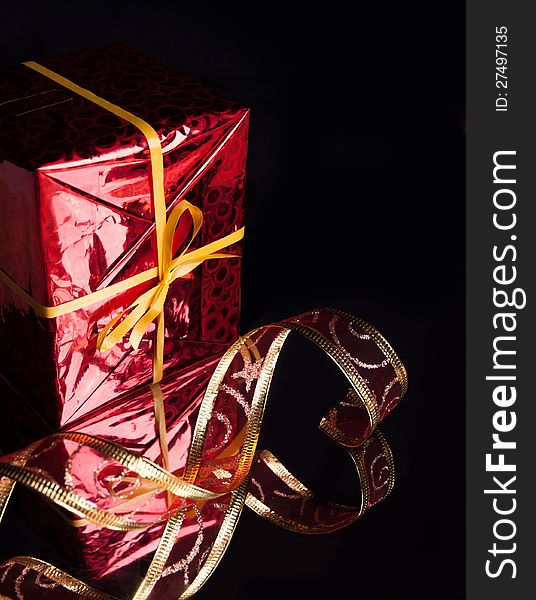 The gift in the red packaging ,delicate red ribbon on a black background with reflection