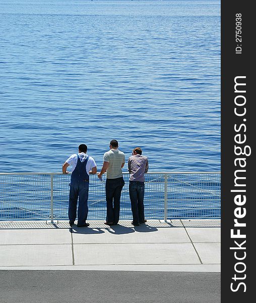 Friends standing on a bridge looking at the calm waters.