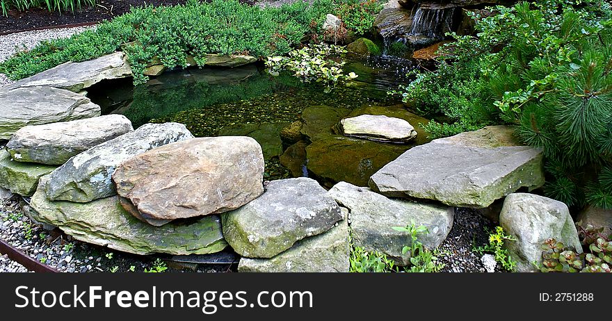 A rock pond surrounded by gravel, with water flowing in one of the famous beacon hill gardens in boston. A rock pond surrounded by gravel, with water flowing in one of the famous beacon hill gardens in boston