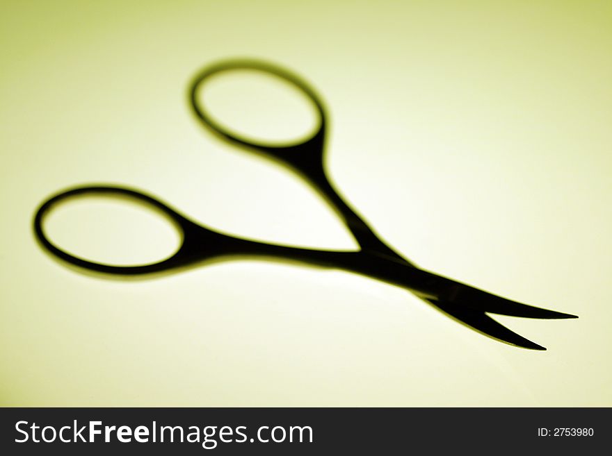 Scissors Silhouette On A Yellow Background, Shallow Depth Of Field, Focus On Front Of The Blade