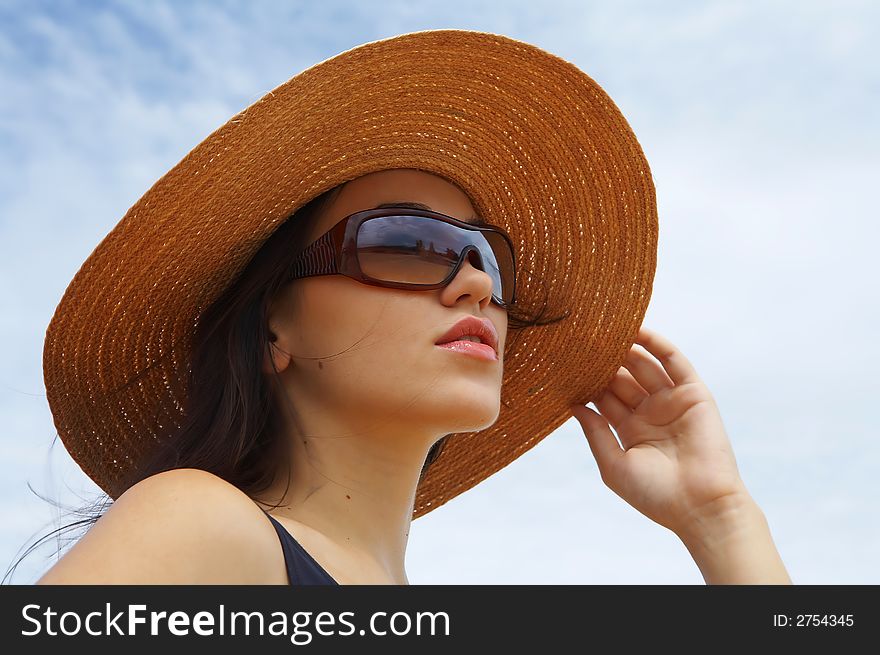 Portrait of young beautiful woman in straw hat and sunglasses