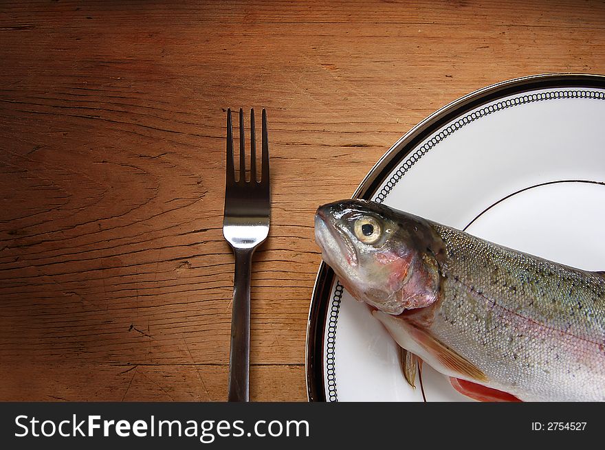 A trout on a plate with a fork. A trout on a plate with a fork.