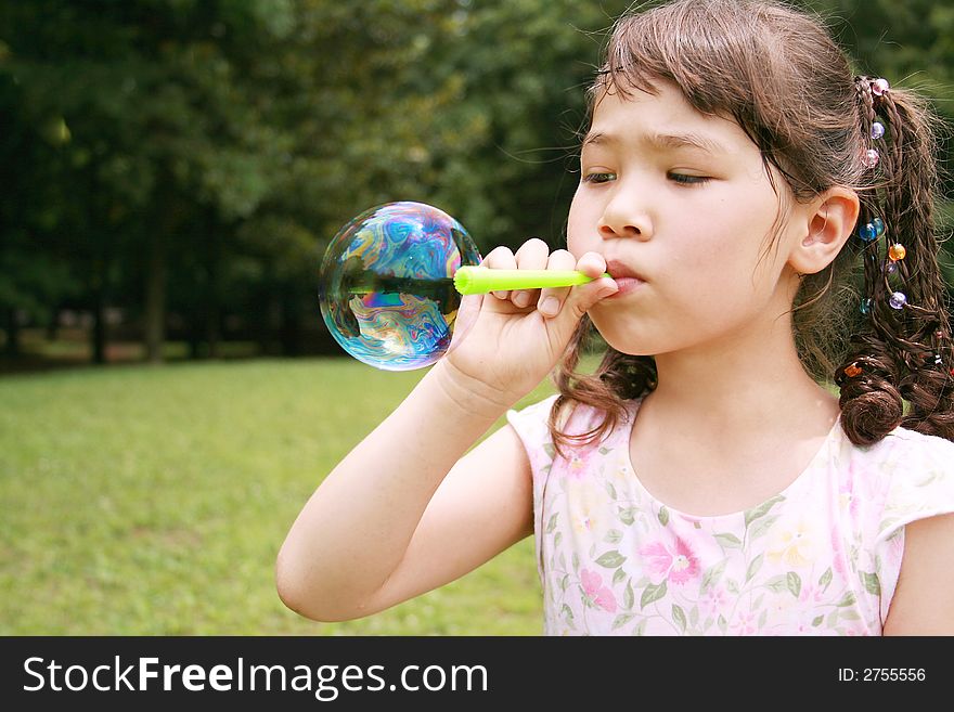 Girl blowing bubble in the park