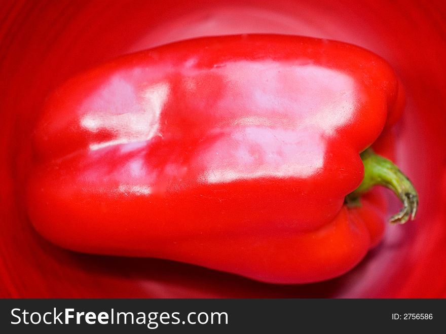 Bright red Bell Pepper against a red background.