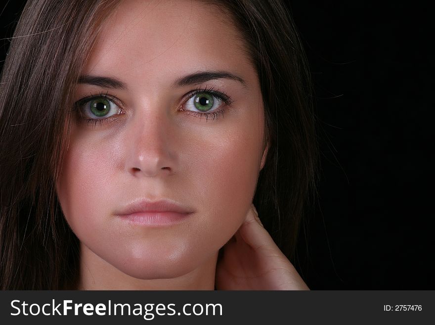 Face of young brunette against black background