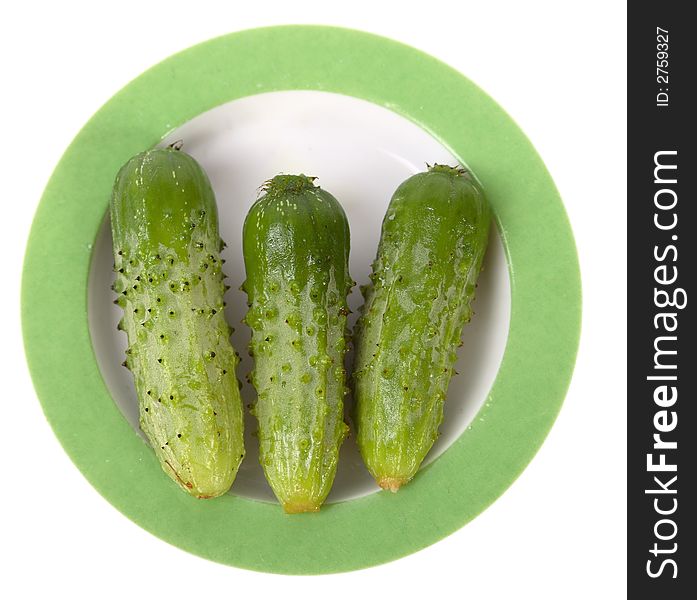 Three little cucumbers on a white saucer isolated