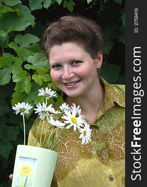 Young smiling girl with vase with camomile. Young smiling girl with vase with camomile