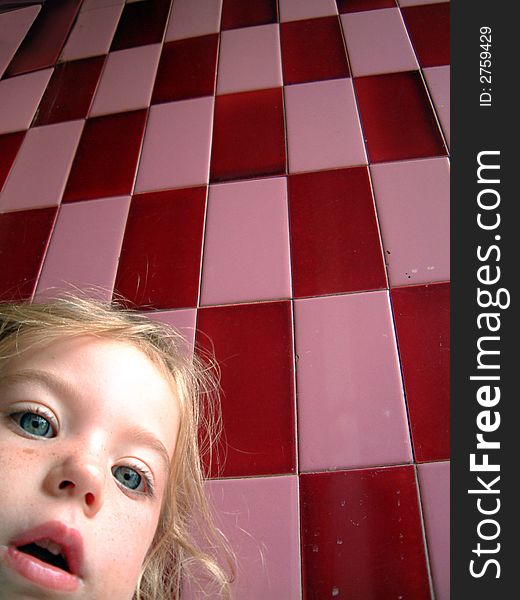 Cute blond little girl and a pink checkered wall as background