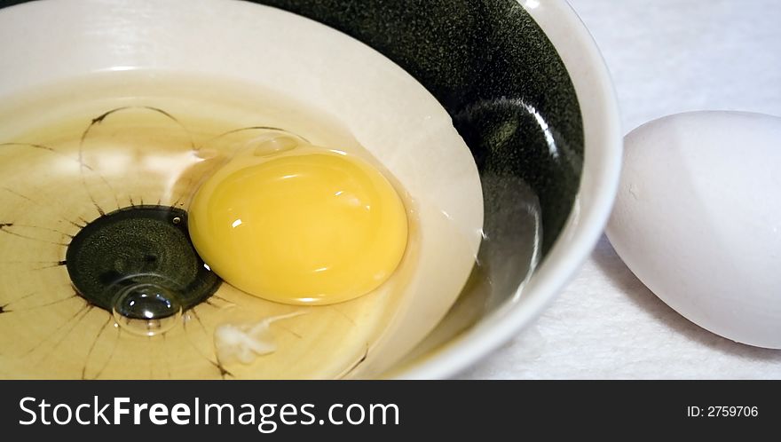 Raw egg in bowl with unbroken egg. Raw egg in bowl with unbroken egg