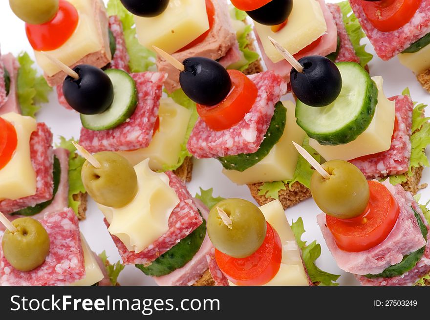 Background of Canape with Bacon, Salami, Tomatoes, Cheese, Cucumber, Green Olive, Black Olive, Lettuce and Whole Grain Bread closeup. Background of Canape with Bacon, Salami, Tomatoes, Cheese, Cucumber, Green Olive, Black Olive, Lettuce and Whole Grain Bread closeup