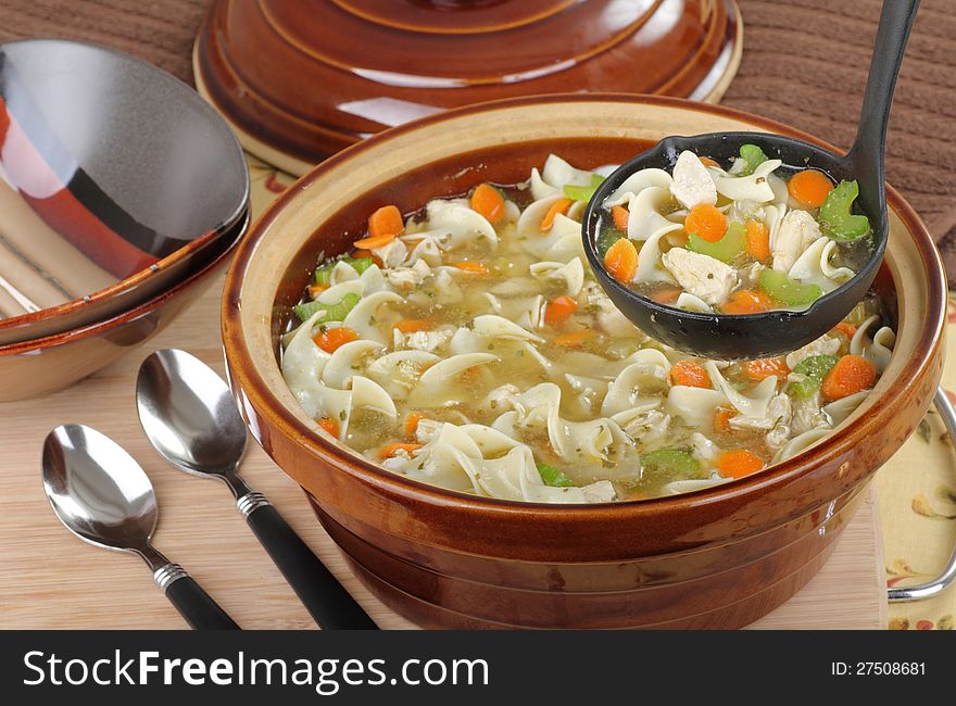 Chicken and noodle soup being served in a ladle. Chicken and noodle soup being served in a ladle