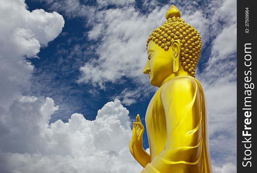 Golden Buddhist statue and blue cloudy sky. Golden Buddhist statue and blue cloudy sky.