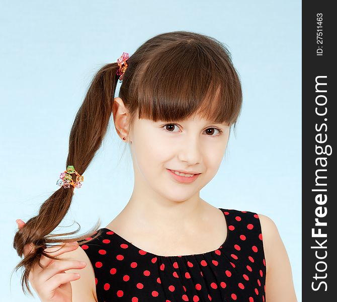 A young girl holds her hair in her hand smiling. A young girl holds her hair in her hand smiling