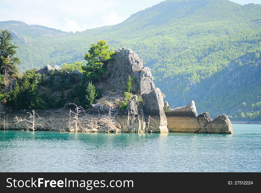 High mountains with growing trees and blue sky and lake. High mountains with growing trees and blue sky and lake