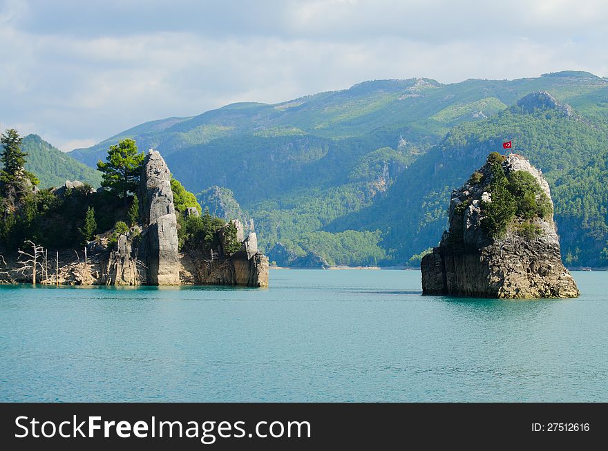 High mountains with growing trees and blue sky and lake. High mountains with growing trees and blue sky and lake