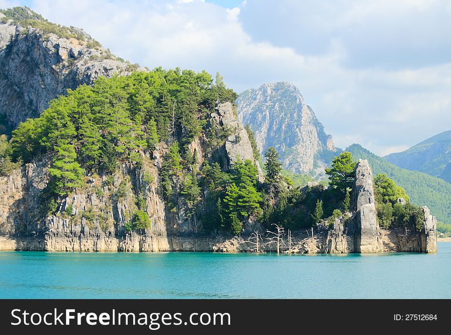 High mountains with growing trees and blue sky and lake. High mountains with growing trees and blue sky and lake