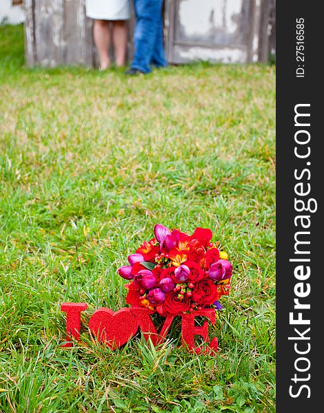 Words spell out love with a bride's bouquet resting upon them after a wedding ceremony. Words spell out love with a bride's bouquet resting upon them after a wedding ceremony.