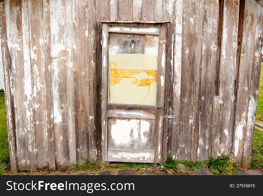 An old building with a peeling paint wood texture and a very old door on a shed or barn creates an abstract background image. An old building with a peeling paint wood texture and a very old door on a shed or barn creates an abstract background image.