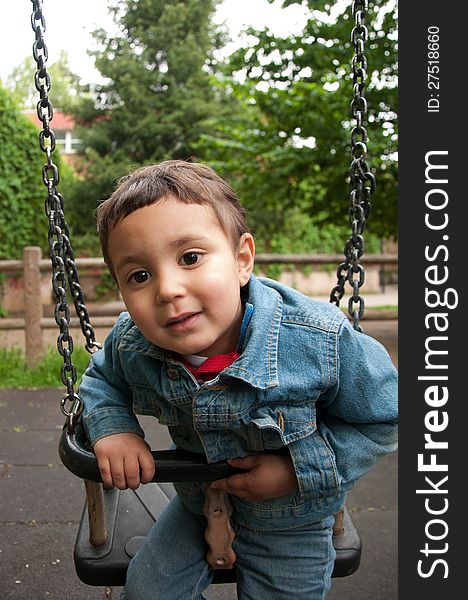 Little Cute Boy Playing On A Swing