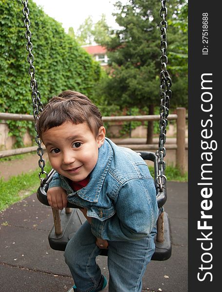 Little cute boy playing on a swing