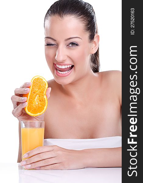 Portrait of young pretty smiling woman holding orange and squeezes the juice from the orange into a glass. Natural fresh juice concept. Portrait of young pretty smiling woman holding orange and squeezes the juice from the orange into a glass. Natural fresh juice concept