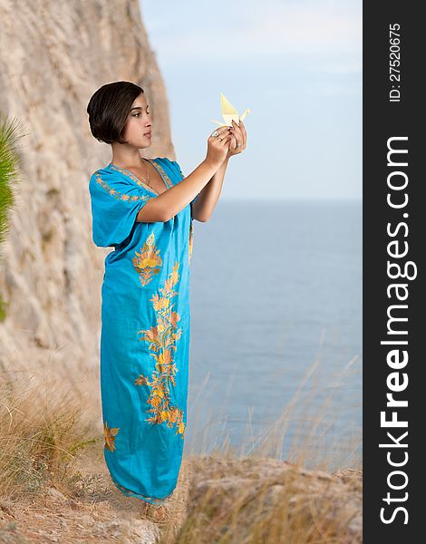 Girl in blue indian dress with origami on seacoast. Girl in blue indian dress with origami on seacoast