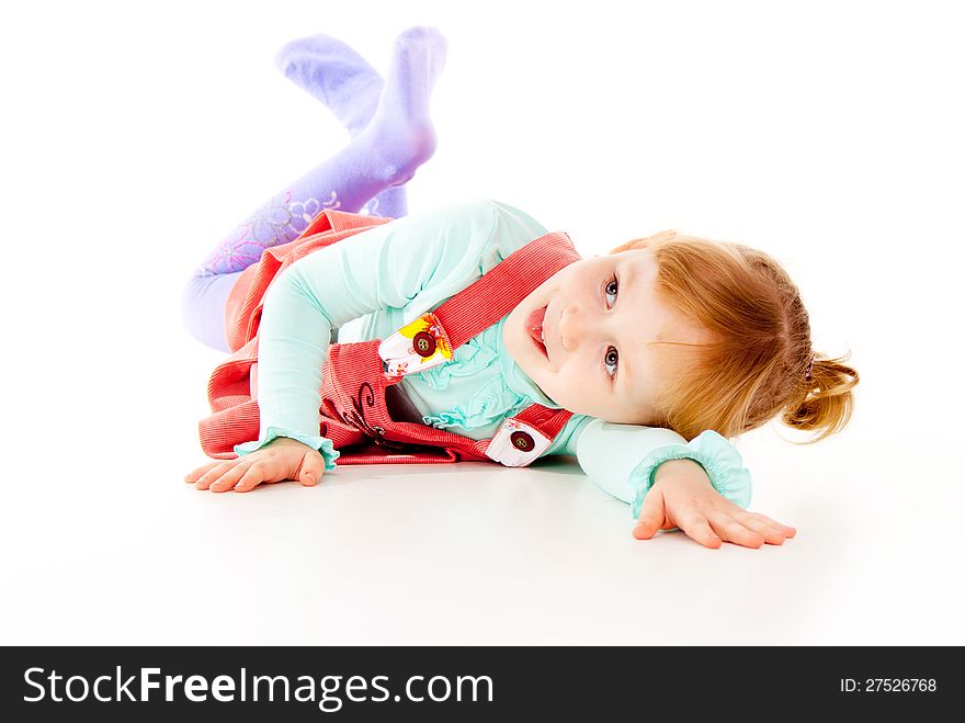 A little girl in a red dress, lying posing isolated on white background