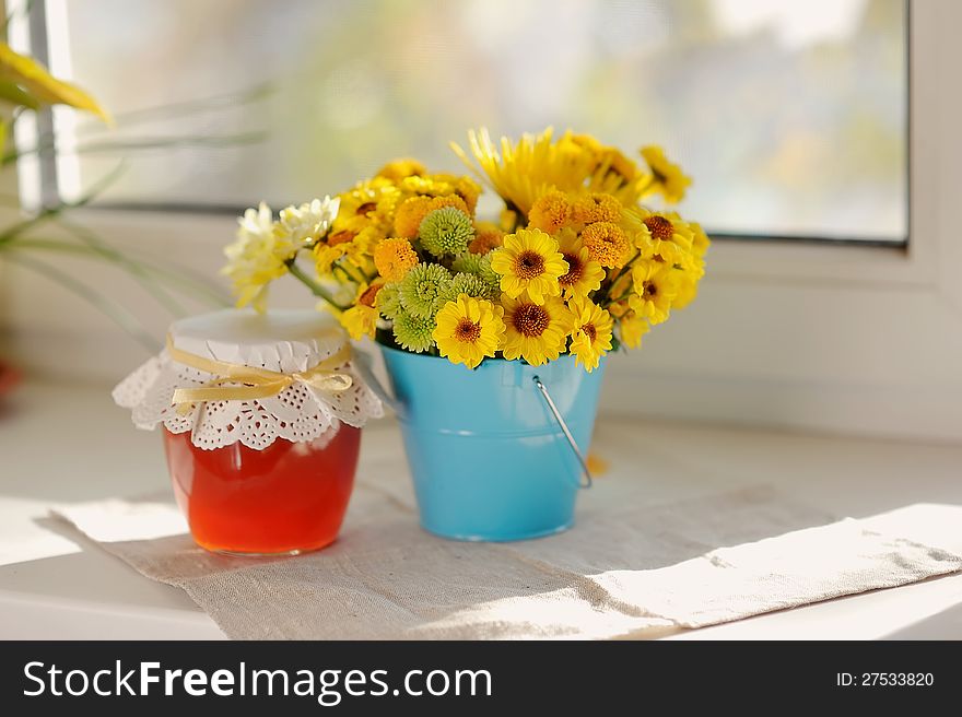 On the window sill in the sun bouquet of yellow flowers and a jar of honey. On the window sill in the sun bouquet of yellow flowers and a jar of honey