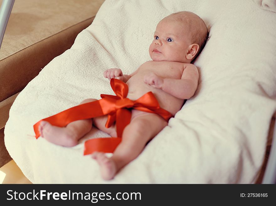 Naked baby lying on a blanket with a red ribbon. Naked baby lying on a blanket with a red ribbon