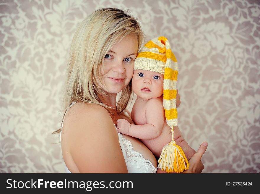 Delicate and feminine mother tenderly hugging her baby in the cap. Delicate and feminine mother tenderly hugging her baby in the cap