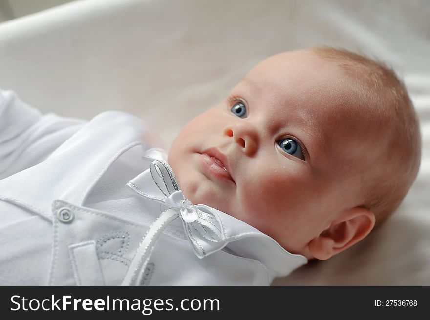 On a white background cute baby lying in a beautiful dress. On a white background cute baby lying in a beautiful dress