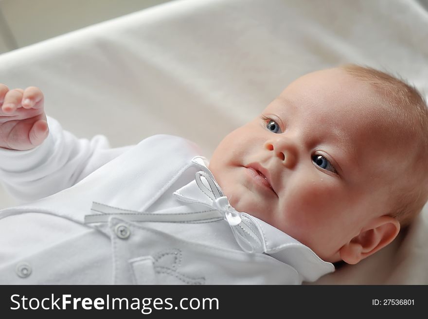 On a white background cute baby lying in a beautiful dress. On a white background cute baby lying in a beautiful dress