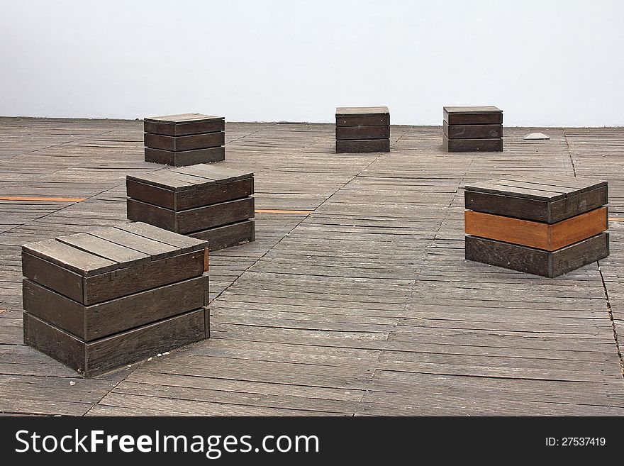 Square wooden chairs on the wooden floor in front of a white wall